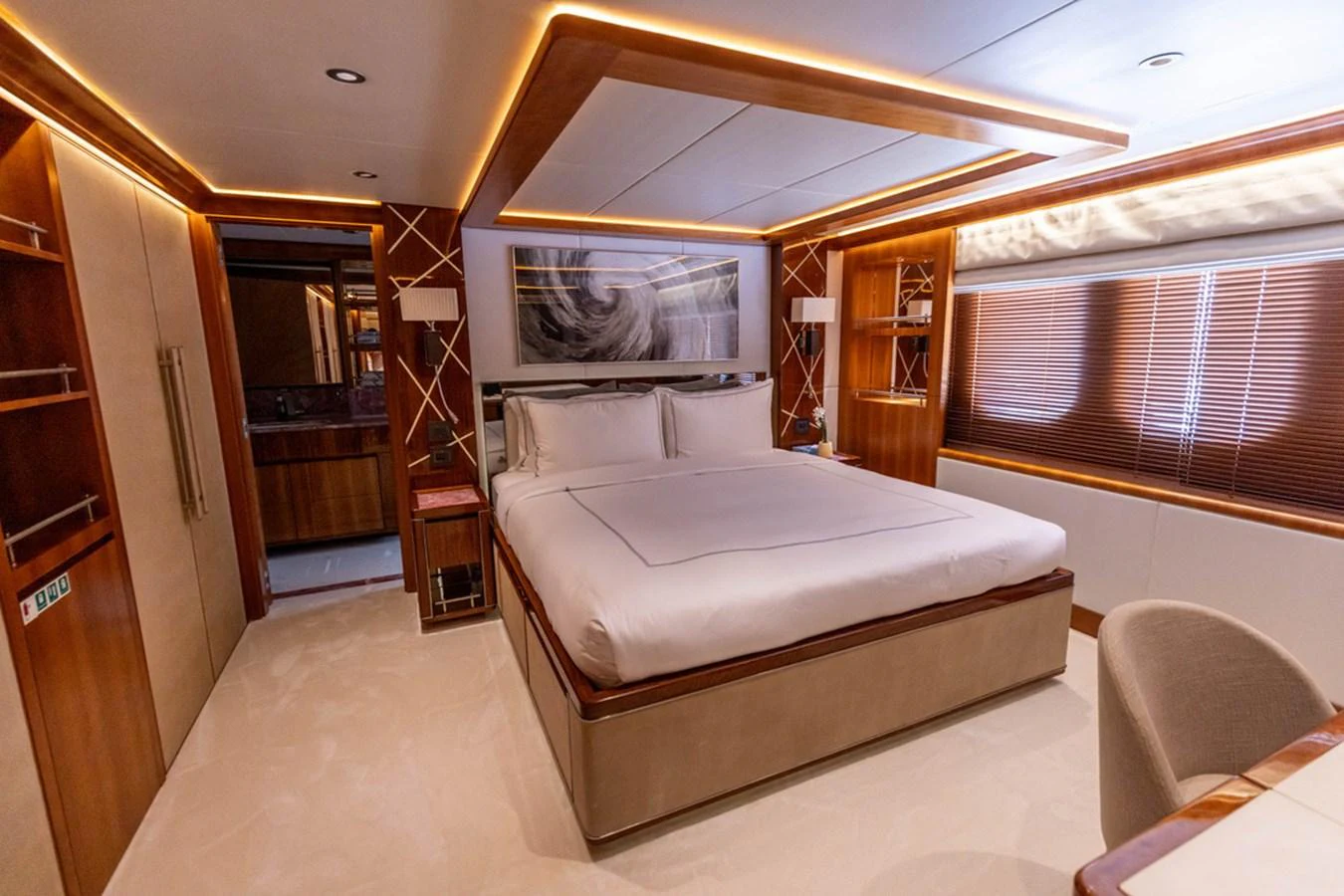 The master stateroom features a luxurious bed with elegant wood accents and ambient lighting. aboard ATLANTIS Yacht for Sale