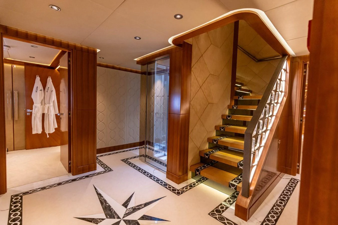 The yacht's interior features a luxurious staircase with elegant wood paneling and intricate floor designs. aboard ATLANTIS Yacht for Sale