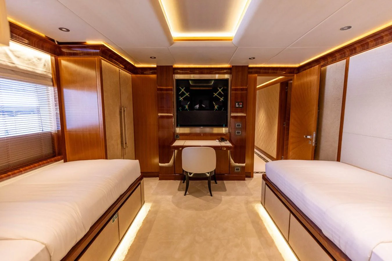 The twin stateroom features two single beds, a desk, and elegant wood paneling. aboard ATLANTIS Yacht for Sale