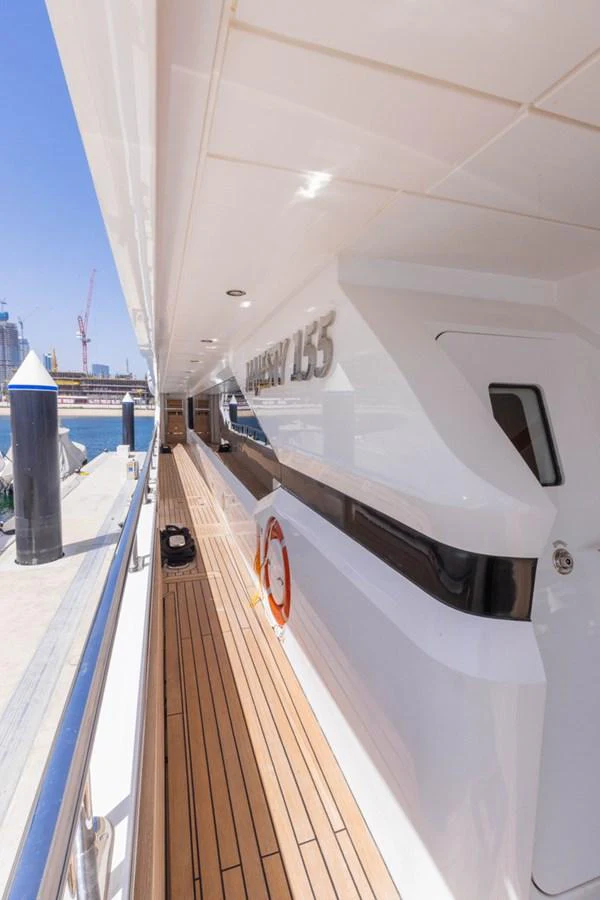 The yacht's sleek side deck features a polished finish and wooden flooring, leading towards the aft. aboard ATLANTIS Yacht for Sale