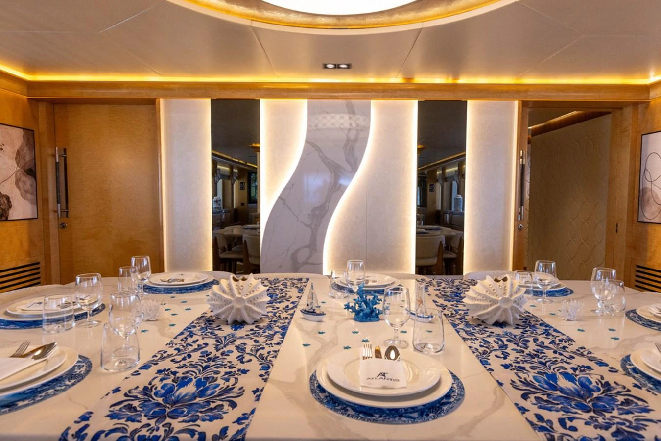The yacht's dining area features an elegant table setting with blue and white accents. aboard ATLANTIS Yacht for Sale