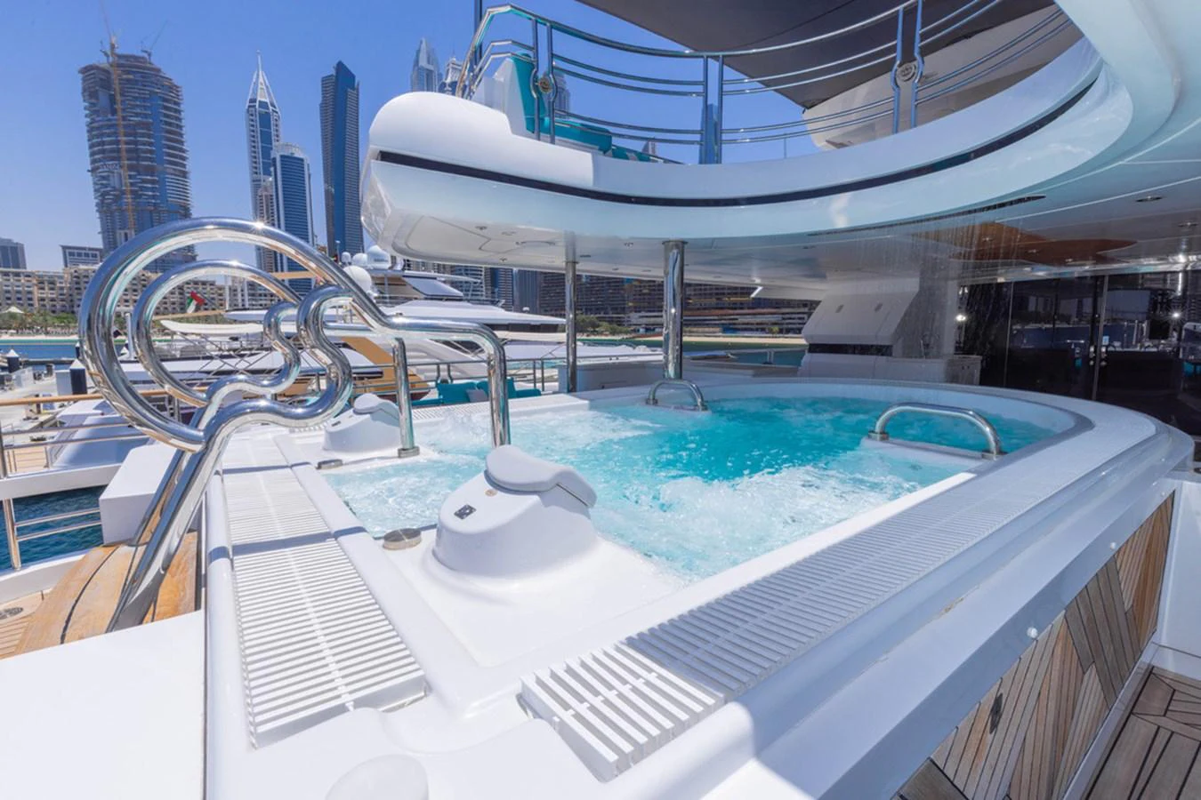 The yacht features a luxurious jacuzzi on the deck with a stunning cityscape backdrop. aboard ATLANTIS Yacht for Sale