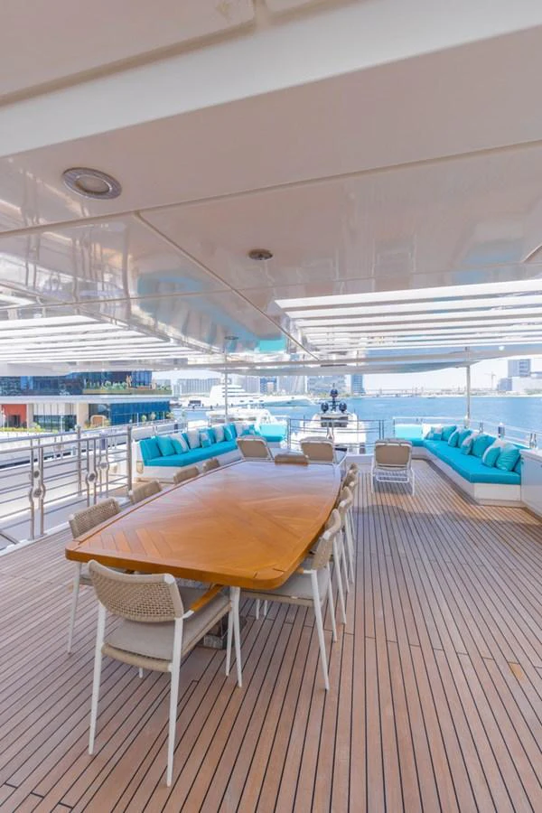The aft deck features a spacious dining area with a large wooden table and comfortable seating, perfect for alfresco dining. aboard ATLANTIS Yacht for Sale
