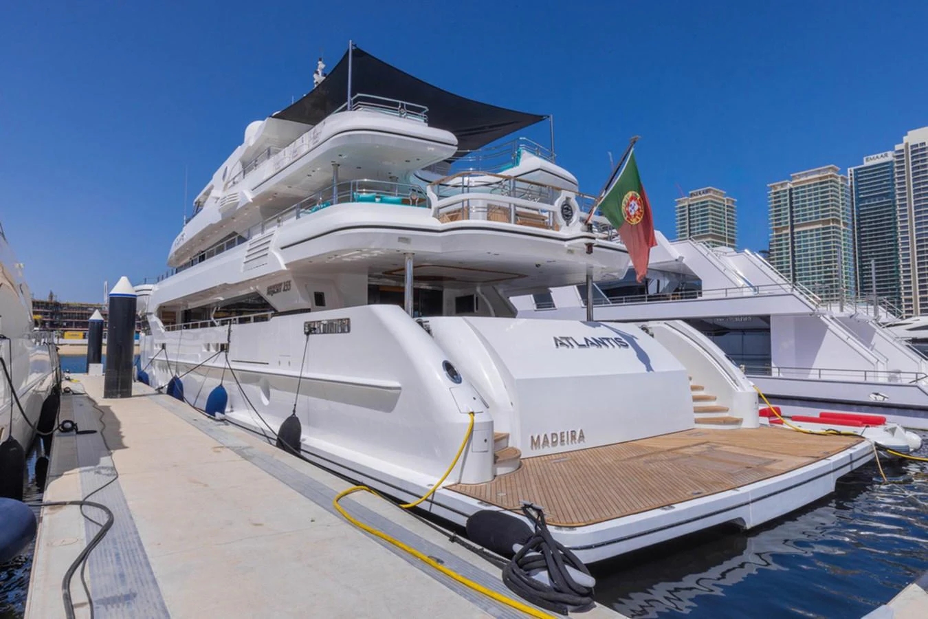 A luxurious yacht docked at a marina, showcasing its spacious aft deck and elegant design. aboard ATLANTIS Yacht for Sale
