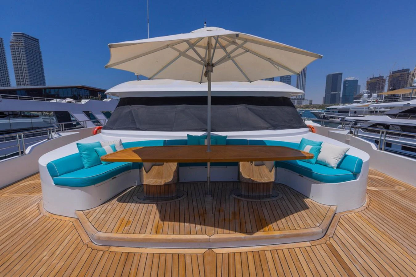 The sundeck features a stylish seating area with a large wooden table and an umbrella for shade. aboard ATLANTIS Yacht for Sale