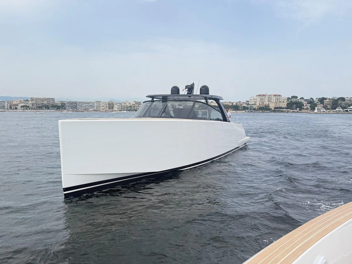A sleek, modern yacht glides smoothly on calm waters with a cityscape in the background. aboard DUTCH PEARL Yacht for Sale