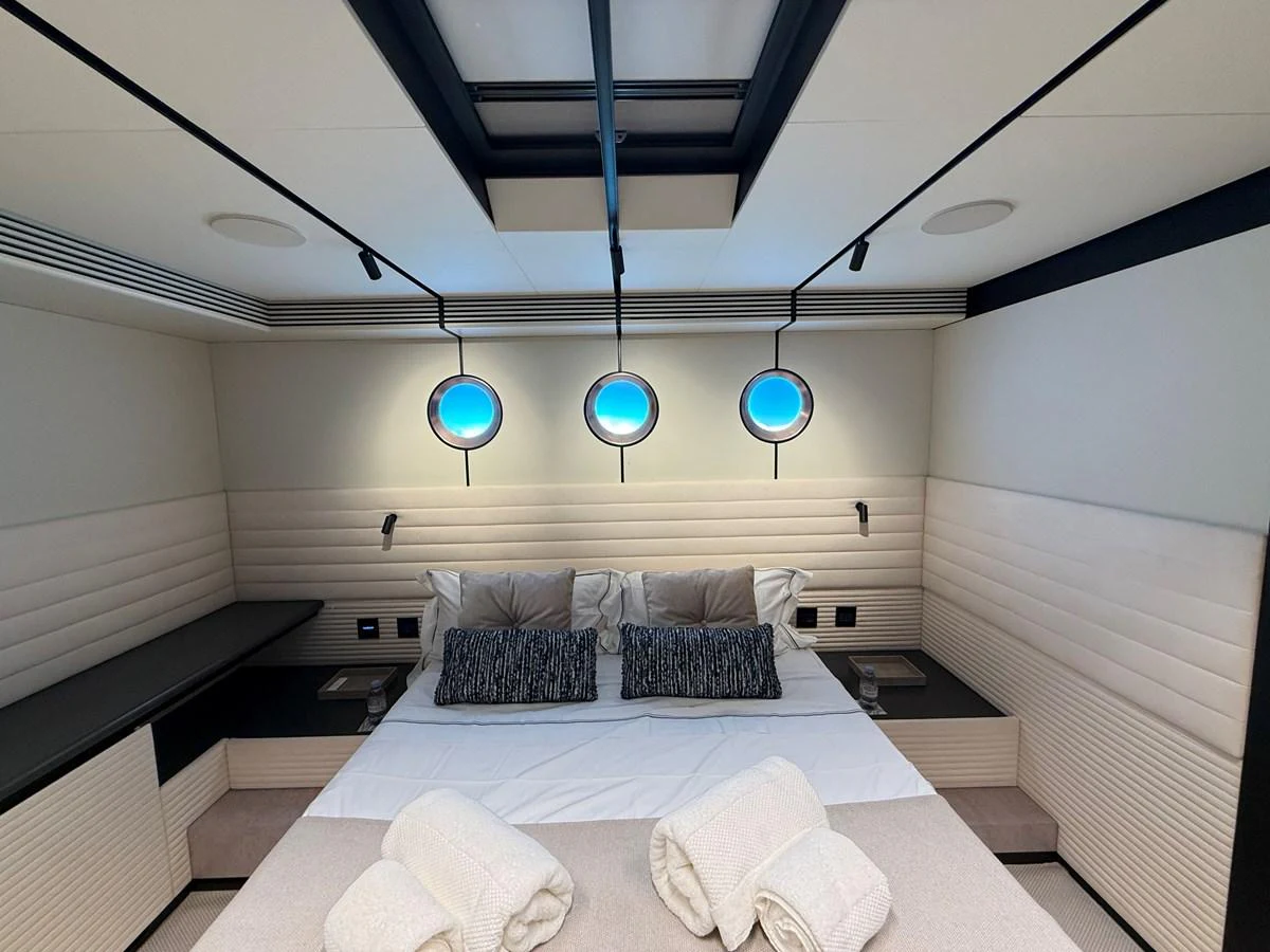 A luxurious stateroom featuring a comfortable bed with elegant lighting and porthole windows. aboard DUTCH PEARL Yacht for Sale