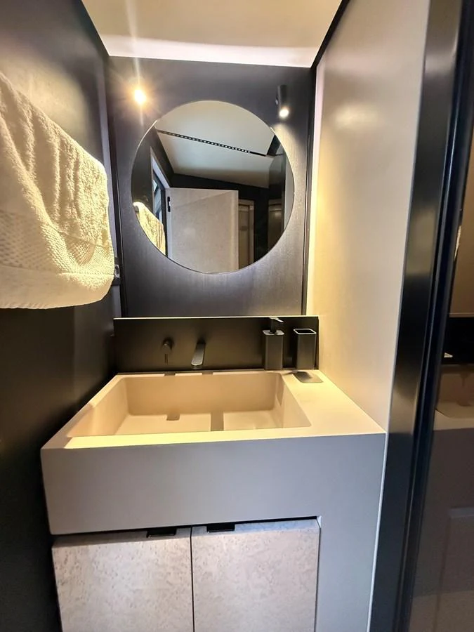 A sleek and modern yacht bathroom featuring a round mirror and contemporary fixtures. aboard DUTCH PEARL Yacht for Sale