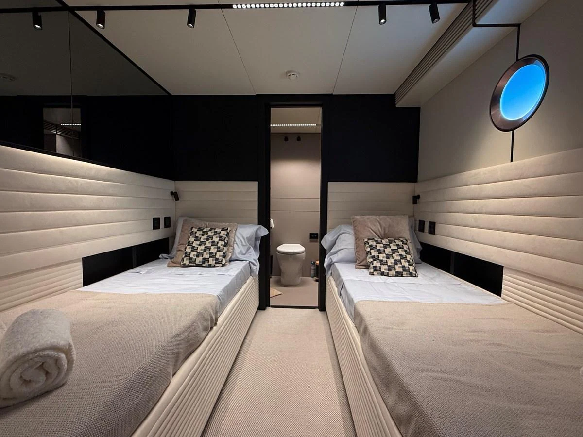 The twin stateroom offers a cozy and modern sleeping area with two single beds and stylish decor. aboard DUTCH PEARL Yacht for Sale