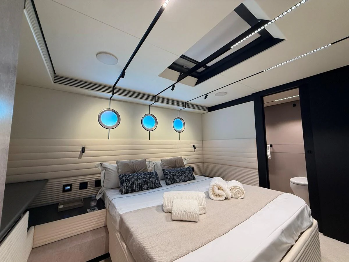 The stateroom features a luxurious bed with modern lighting and porthole windows, creating a serene and inviting atmosphere. aboard DUTCH PEARL Yacht for Sale