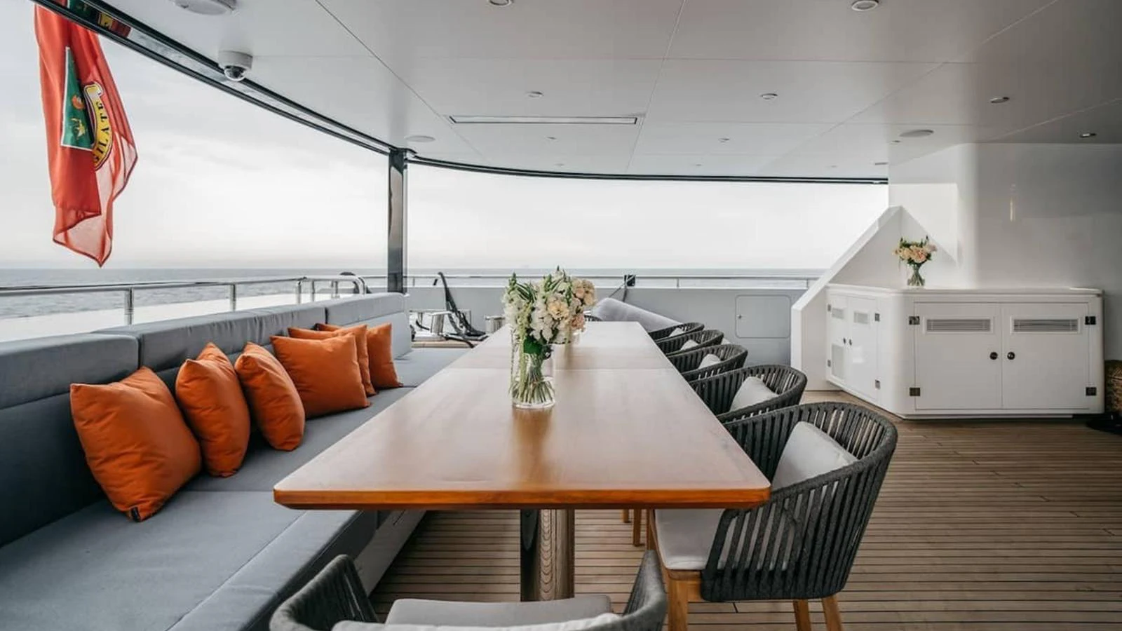 The aft deck features a stylish dining area with a wooden table and comfortable seating, perfect for alfresco meals. aboard HEEUS Yacht for Sale