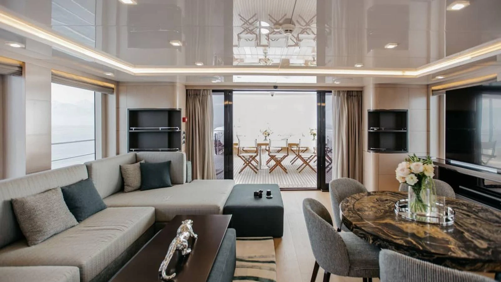 The yacht's interior features a spacious and elegantly designed living area with modern furnishings and a dining space. aboard HEEUS Yacht for Sale