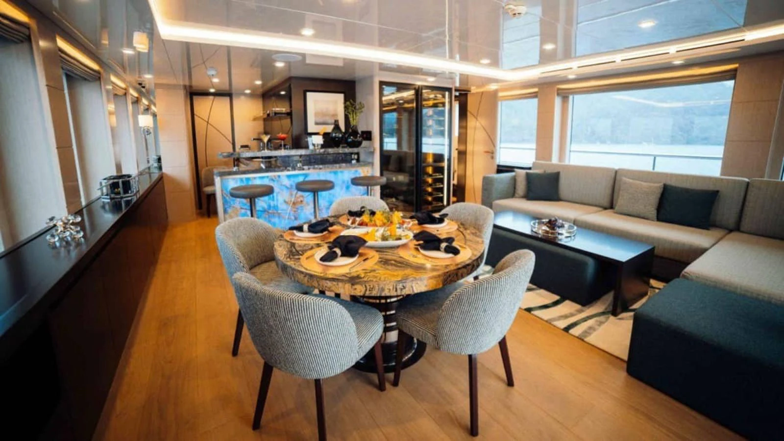 The salon features a stylish dining area with a round table and a comfortable lounge space. aboard HEEUS Yacht for Sale