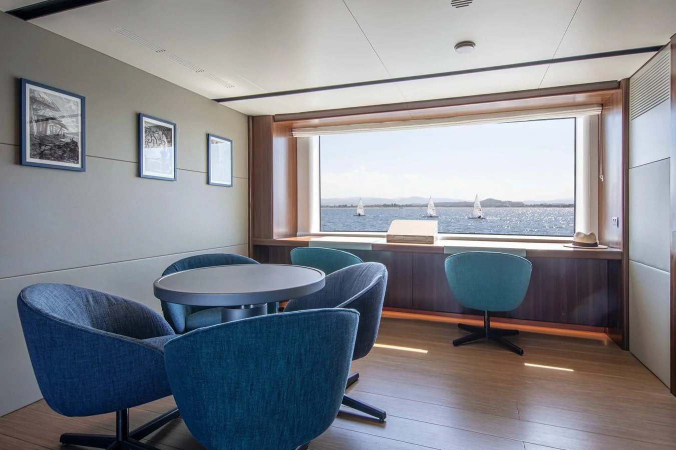 A stylish lounge area with modern seating and a large window offering a stunning sea view. aboard JULES Yacht for Sale