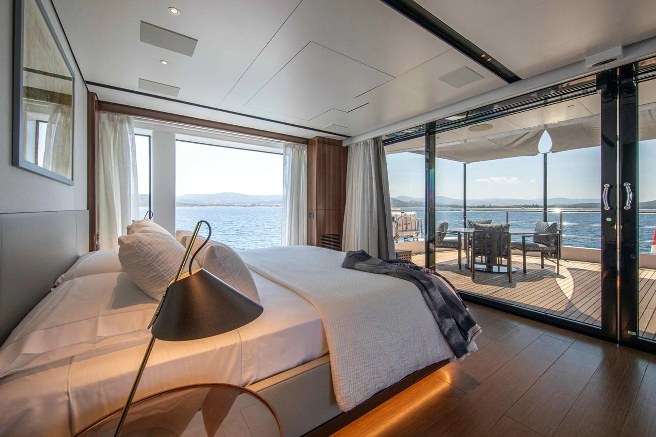 A luxurious stateroom with a stunning view of the sea through large glass doors. aboard JULES Yacht for Sale