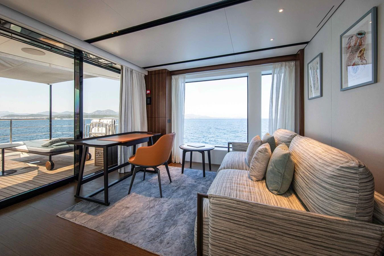 The salon offers a comfortable seating area with a stunning view of the ocean through large windows. aboard JULES Yacht for Sale