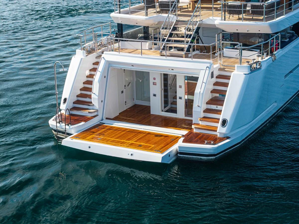 The yacht's aft deck features a spacious swim platform and elegant wooden steps leading to the upper levels. aboard JULES Yacht for Sale