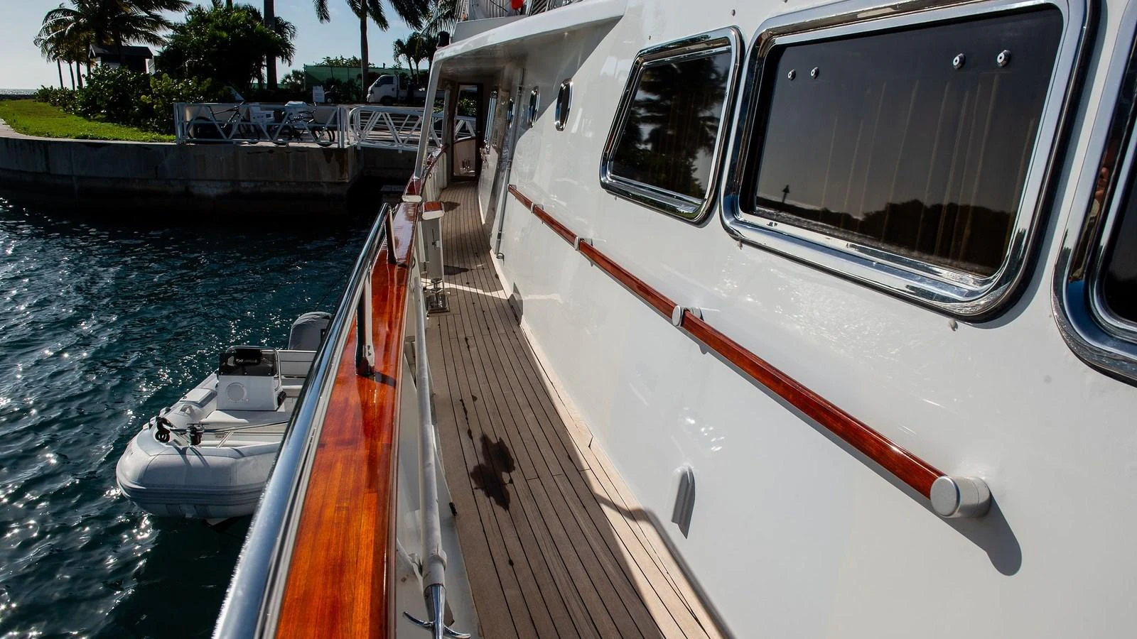 The yacht's side deck offers a sleek passageway with polished wood accents and a view of the tender. aboard SISISI Yacht for Sale