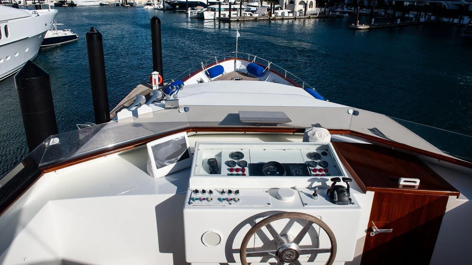 The helm station offers a commanding view of the marina, featuring modern navigation equipment and a classic wooden steering wheel. aboard SISISI Yacht for Sale