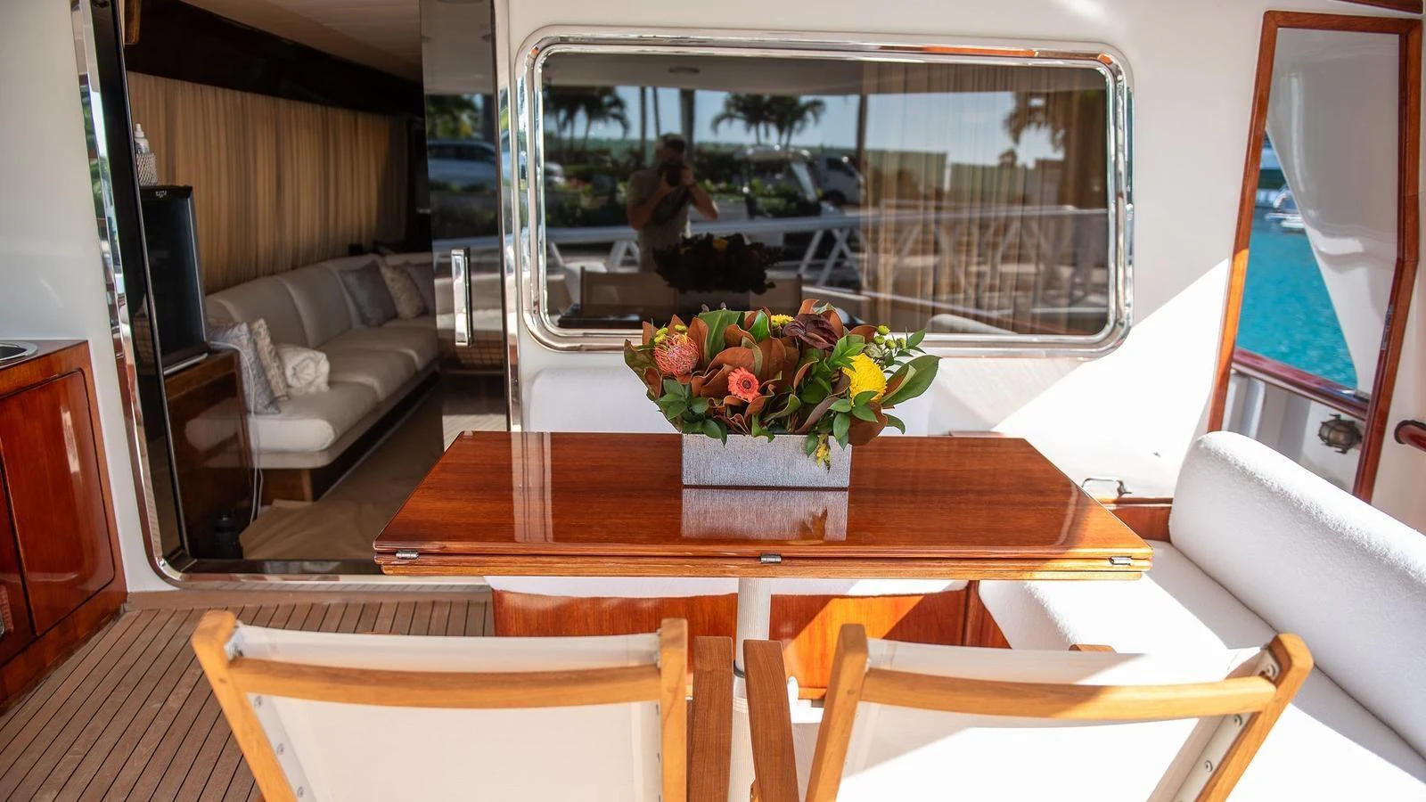The aft deck features a cozy seating area with a polished wooden table adorned with a floral arrangement. aboard SISISI Yacht for Sale