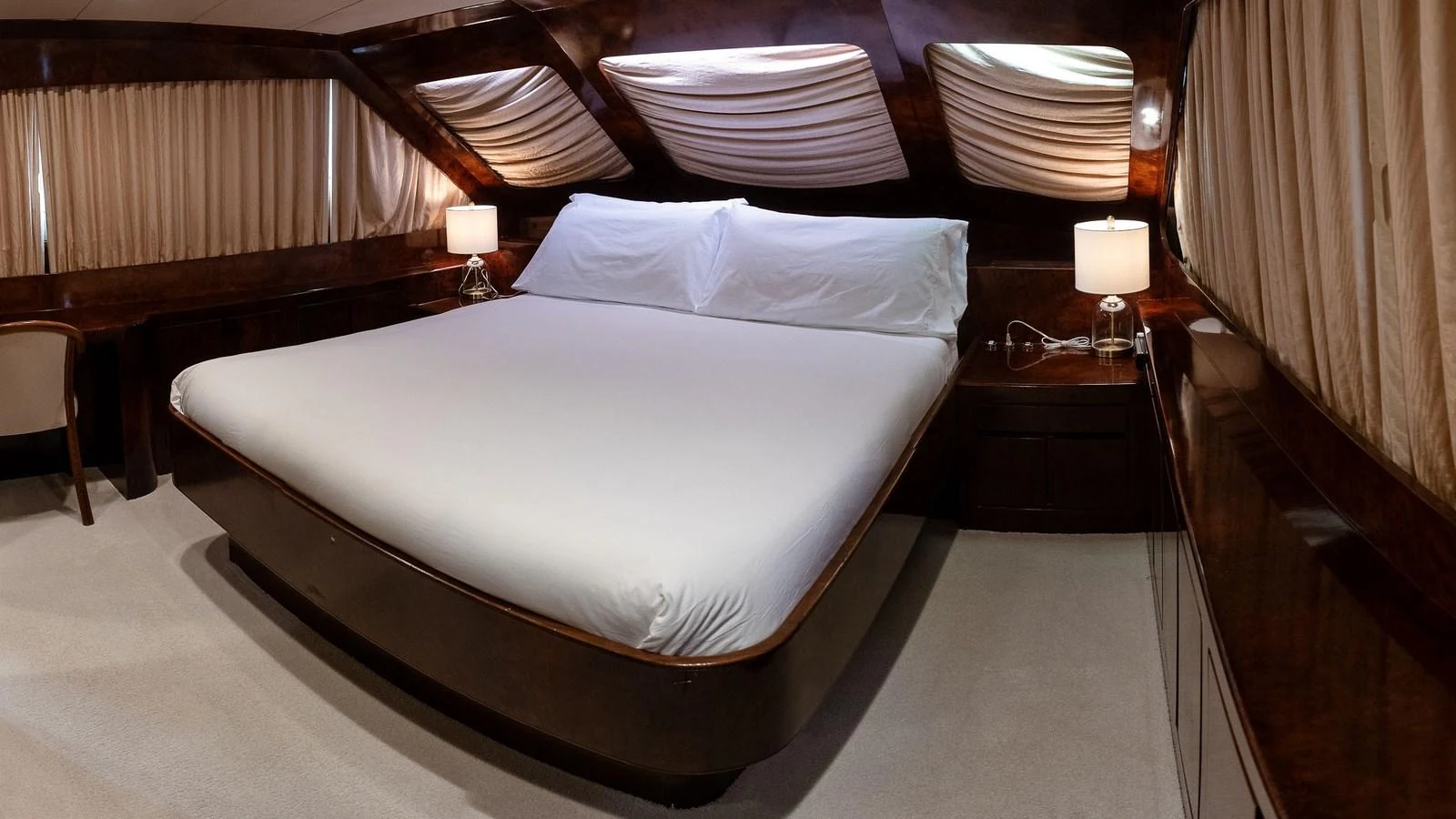 The stateroom features a luxurious bed with elegant lighting and rich wood finishes. aboard SISISI Yacht for Sale