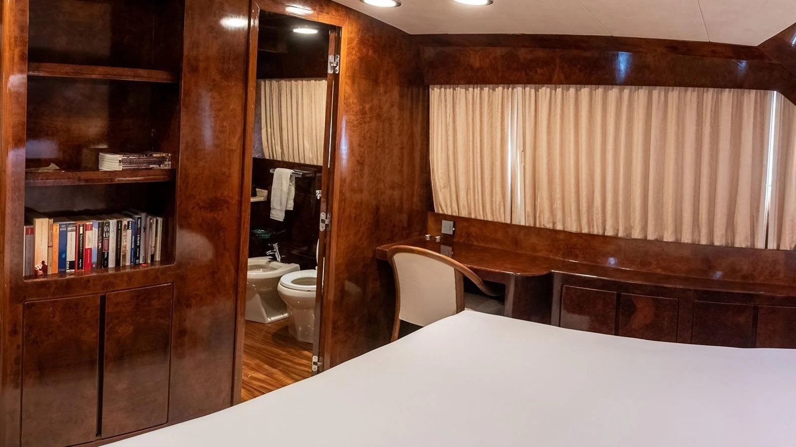 A cozy stateroom with rich wood paneling, a desk, and an ensuite bathroom. aboard SISISI Yacht for Sale
