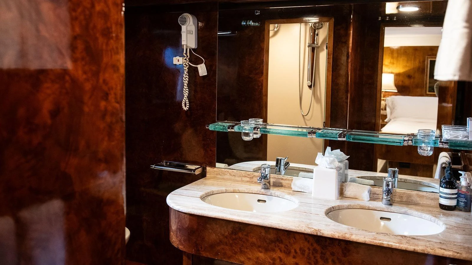 The yacht's bathroom features elegant wood paneling and dual sinks with a modern design. aboard SISISI Yacht for Sale