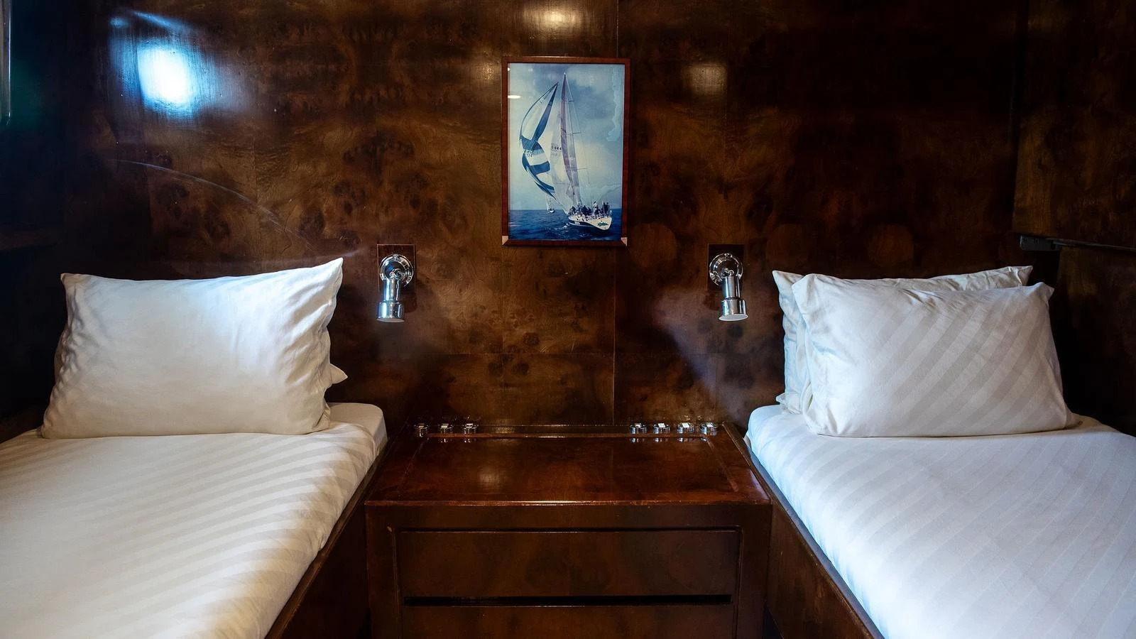 A cozy twin cabin with rich wood paneling and nautical artwork. aboard SISISI Yacht for Sale