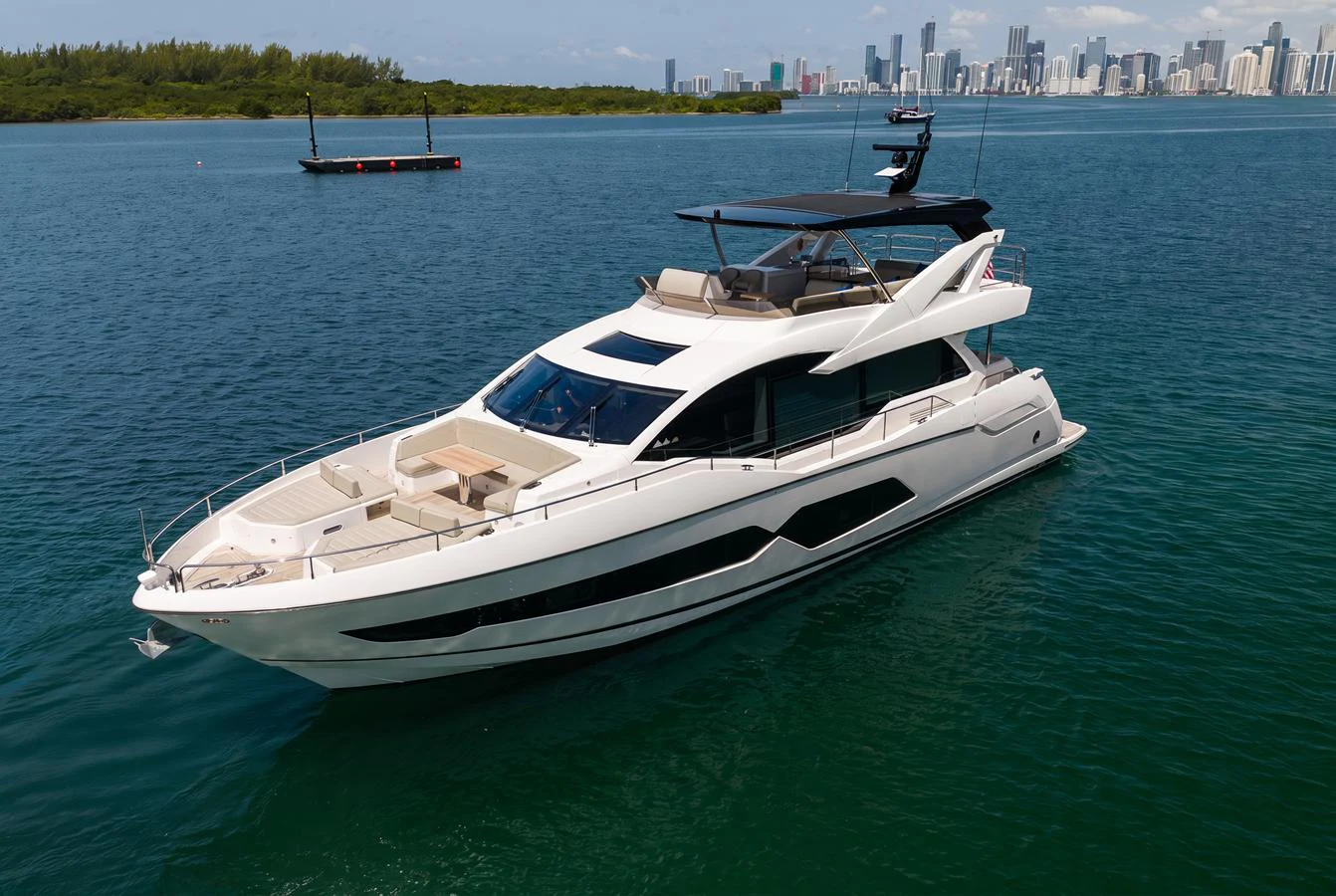 A sleek and modern yacht cruising on calm waters with a city skyline in the background. aboard BAZINGA Yacht for Sale