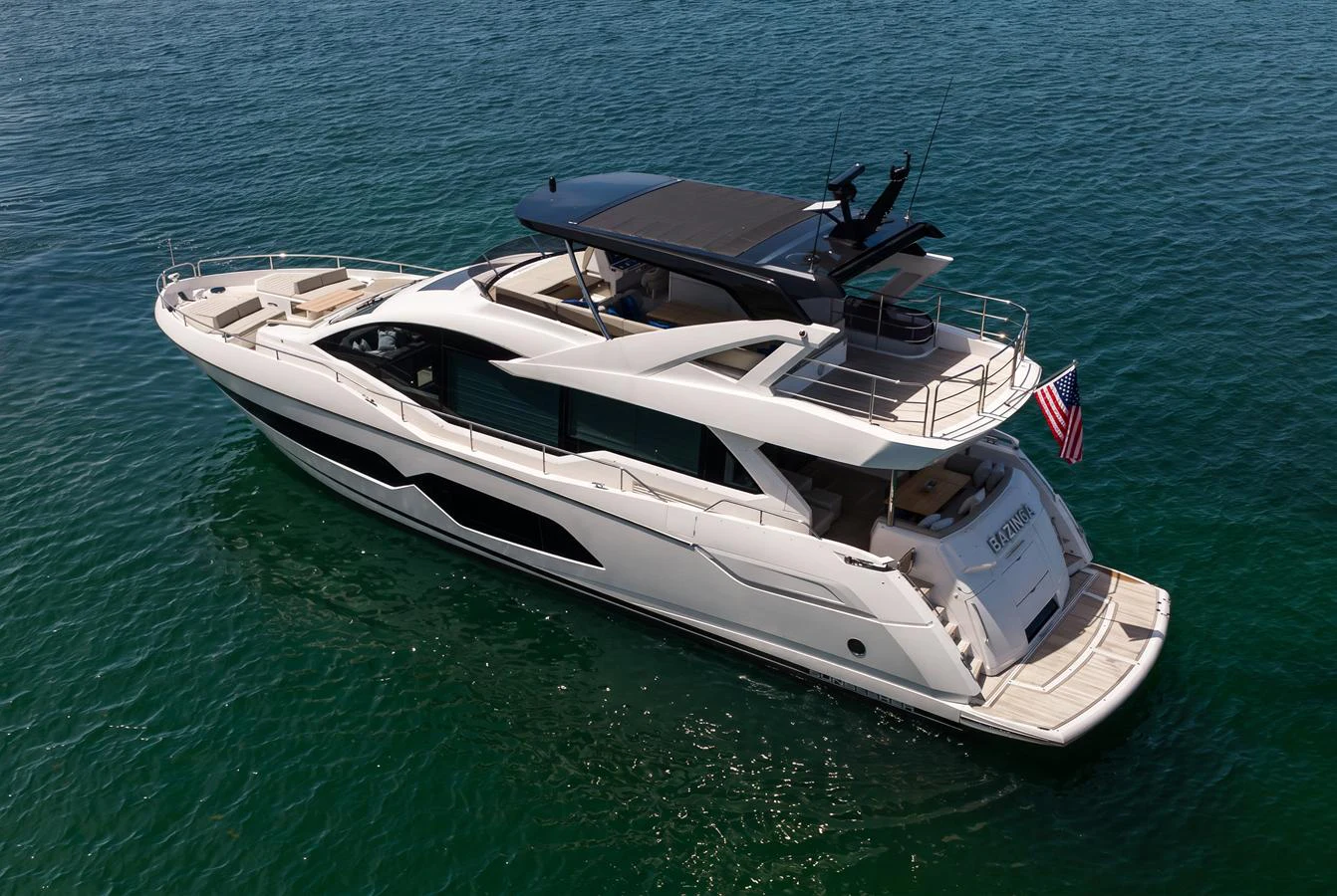 A sleek and modern yacht cruising on calm waters, showcasing its elegant design and spacious deck areas. aboard BAZINGA Yacht for Sale