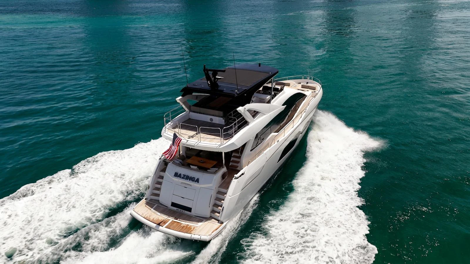 A sleek yacht cruises through turquoise waters, showcasing its elegant design and spacious deck. aboard BAZINGA Yacht for Sale