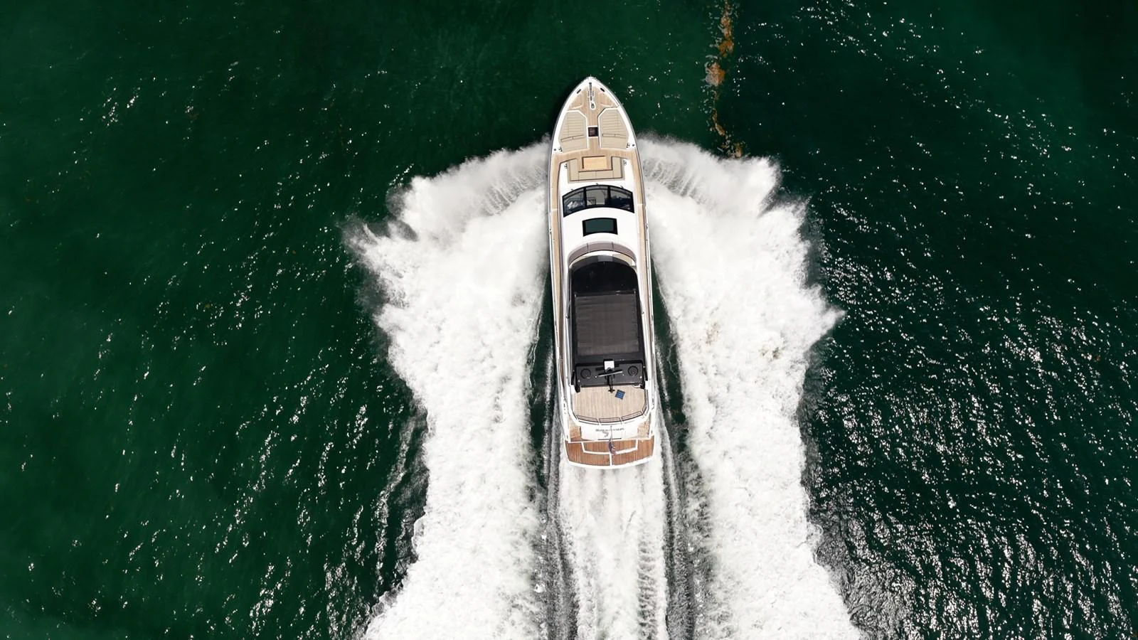 An elegant yacht cuts through the water, leaving a dynamic wake behind. aboard BAZINGA Yacht for Sale