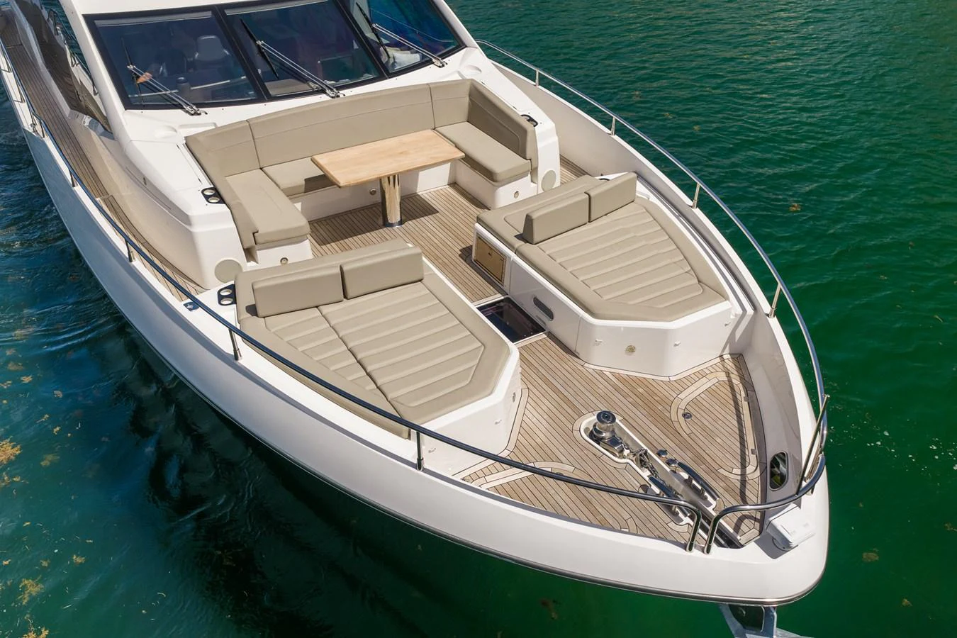 The foredeck of this yacht features spacious sun pads and a comfortable seating area with a table, perfect for relaxation and socializing. aboard BAZINGA Yacht for Sale