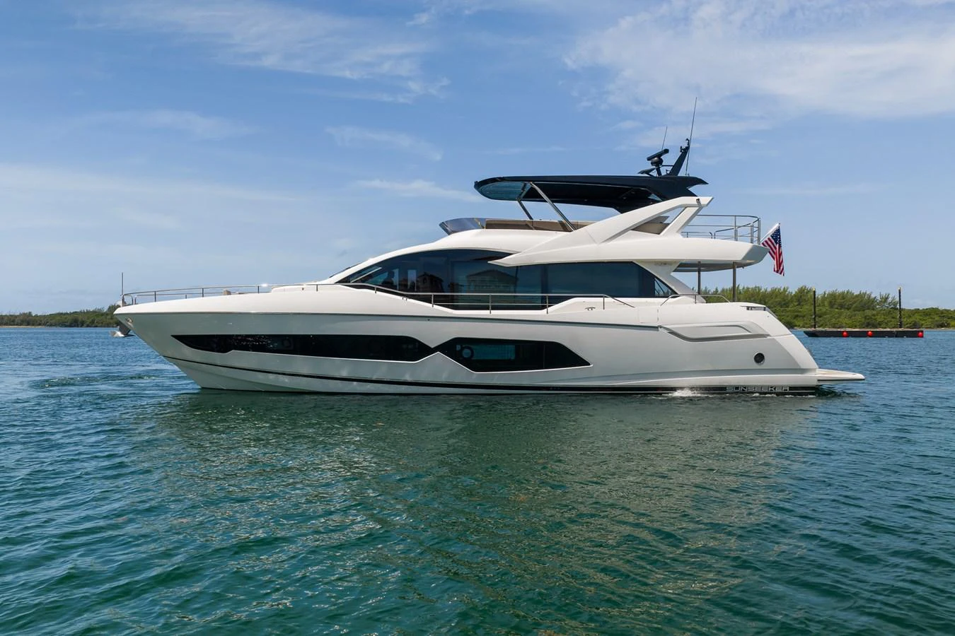 A sleek and modern yacht cruising on calm waters under a clear blue sky. aboard BAZINGA Yacht for Sale