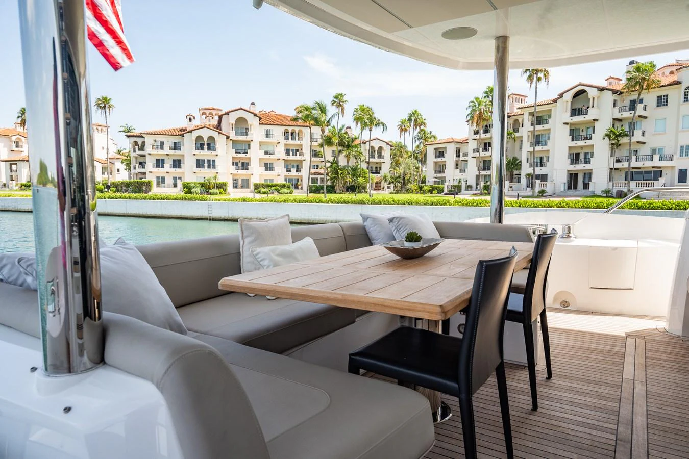 The aft deck features a comfortable seating area with a wooden dining table, perfect for alfresco dining with a view of the waterfront. aboard BAZINGA Yacht for Sale
