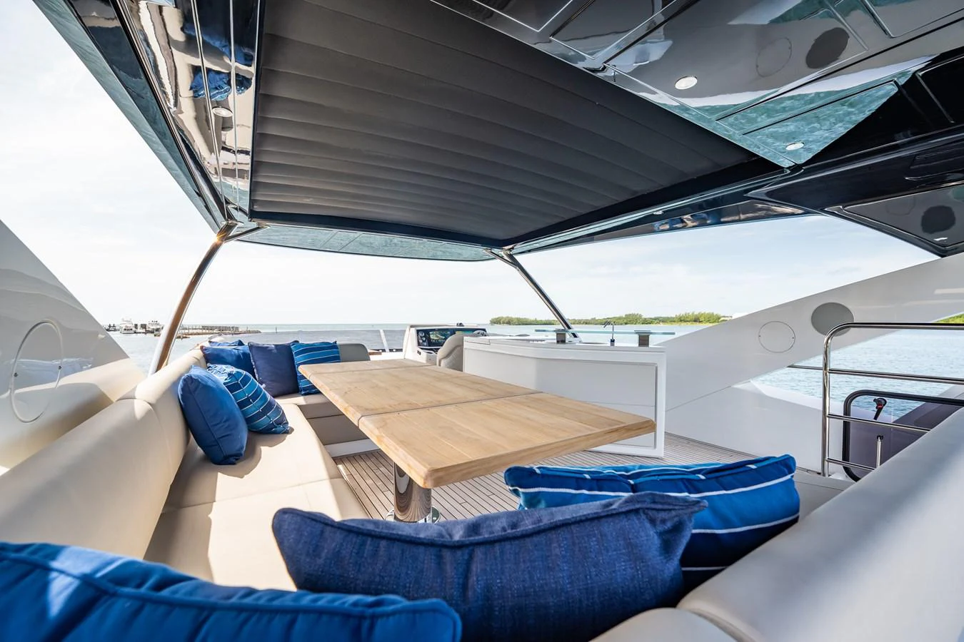 The flybridge offers a spacious seating area with plush cushions and a wooden table, perfect for outdoor relaxation. aboard BAZINGA Yacht for Sale