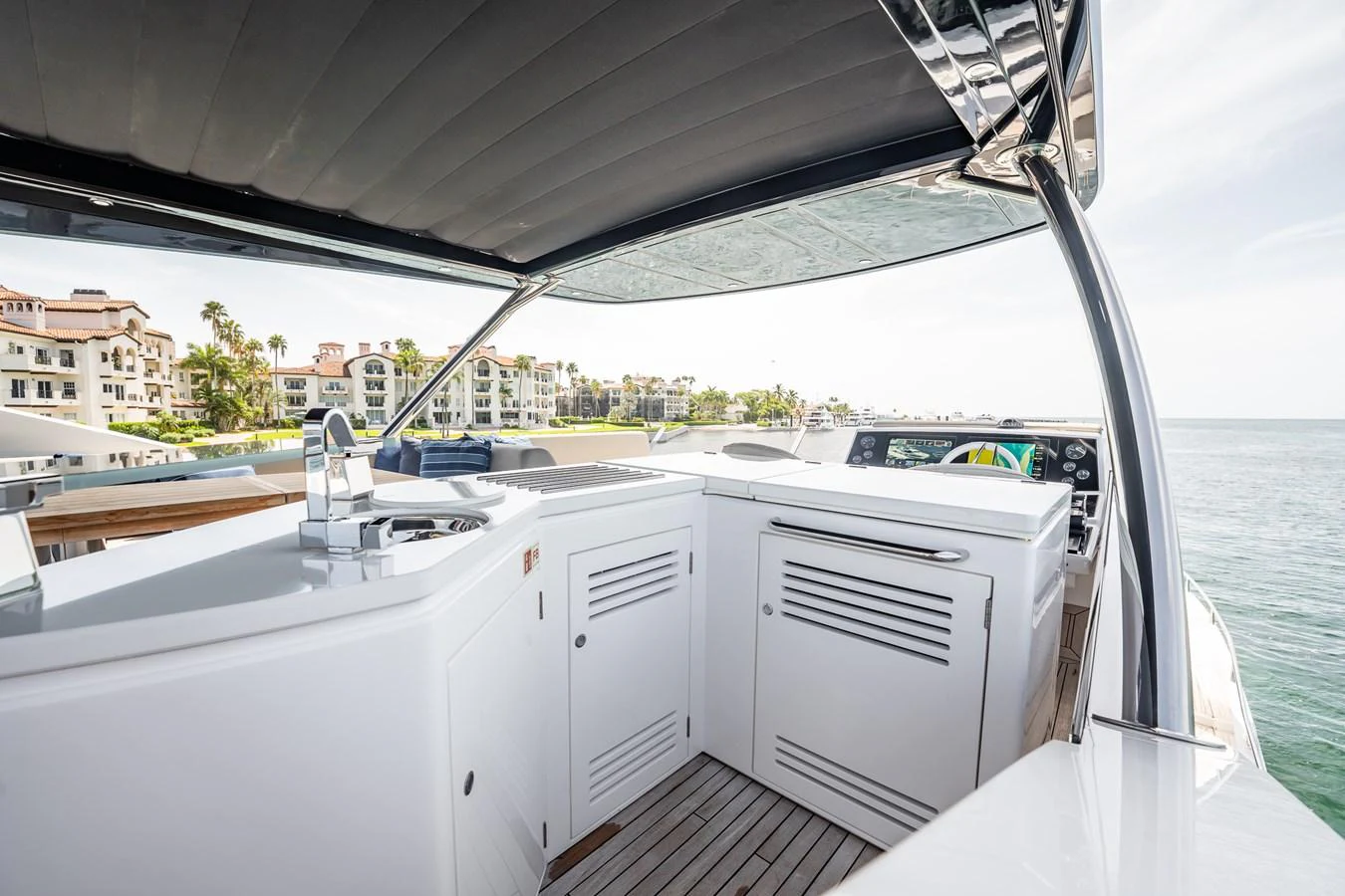 The flybridge offers a sleek and modern outdoor kitchen area with a view of the surrounding waters and nearby buildings. aboard BAZINGA Yacht for Sale