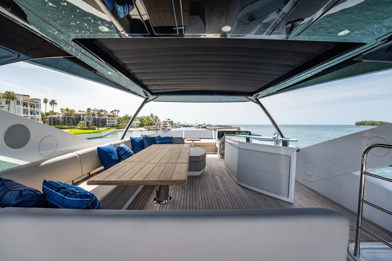 The flybridge offers a spacious and luxurious outdoor seating area with a dining table and bar, perfect for entertaining while enjoying panoramic views. aboard BAZINGA Yacht for Sale