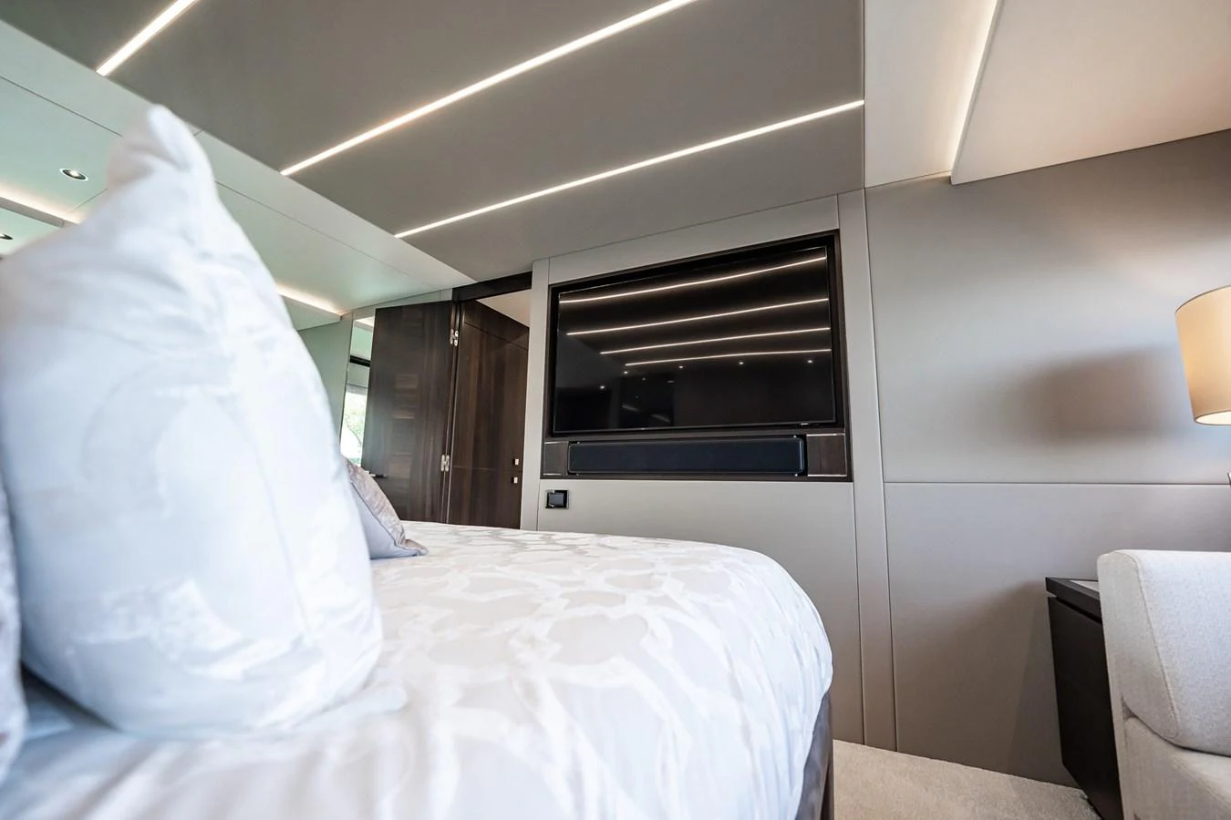 The stateroom features a luxurious bed with elegant linens and modern lighting. aboard BAZINGA Yacht for Sale