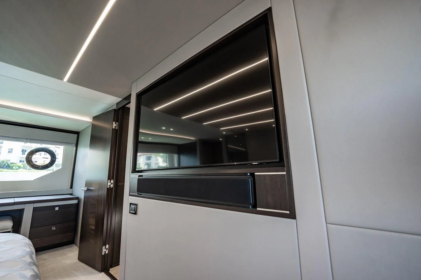 The modern interior features a sleek entertainment area with a large flat-screen TV and stylish cabinetry. aboard BAZINGA Yacht for Sale