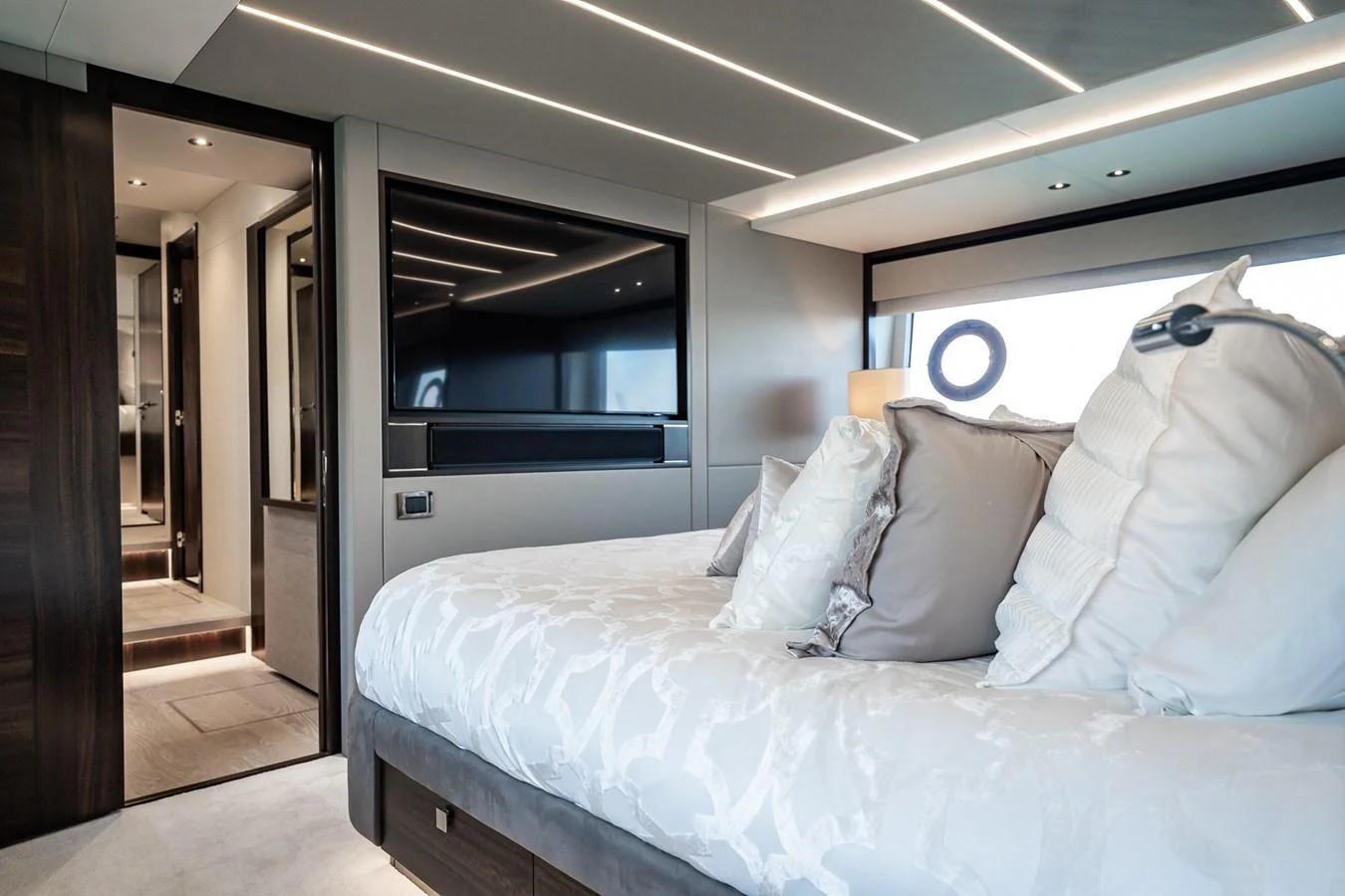 The master stateroom features a luxurious bed with plush pillows and modern lighting. aboard BAZINGA Yacht for Sale