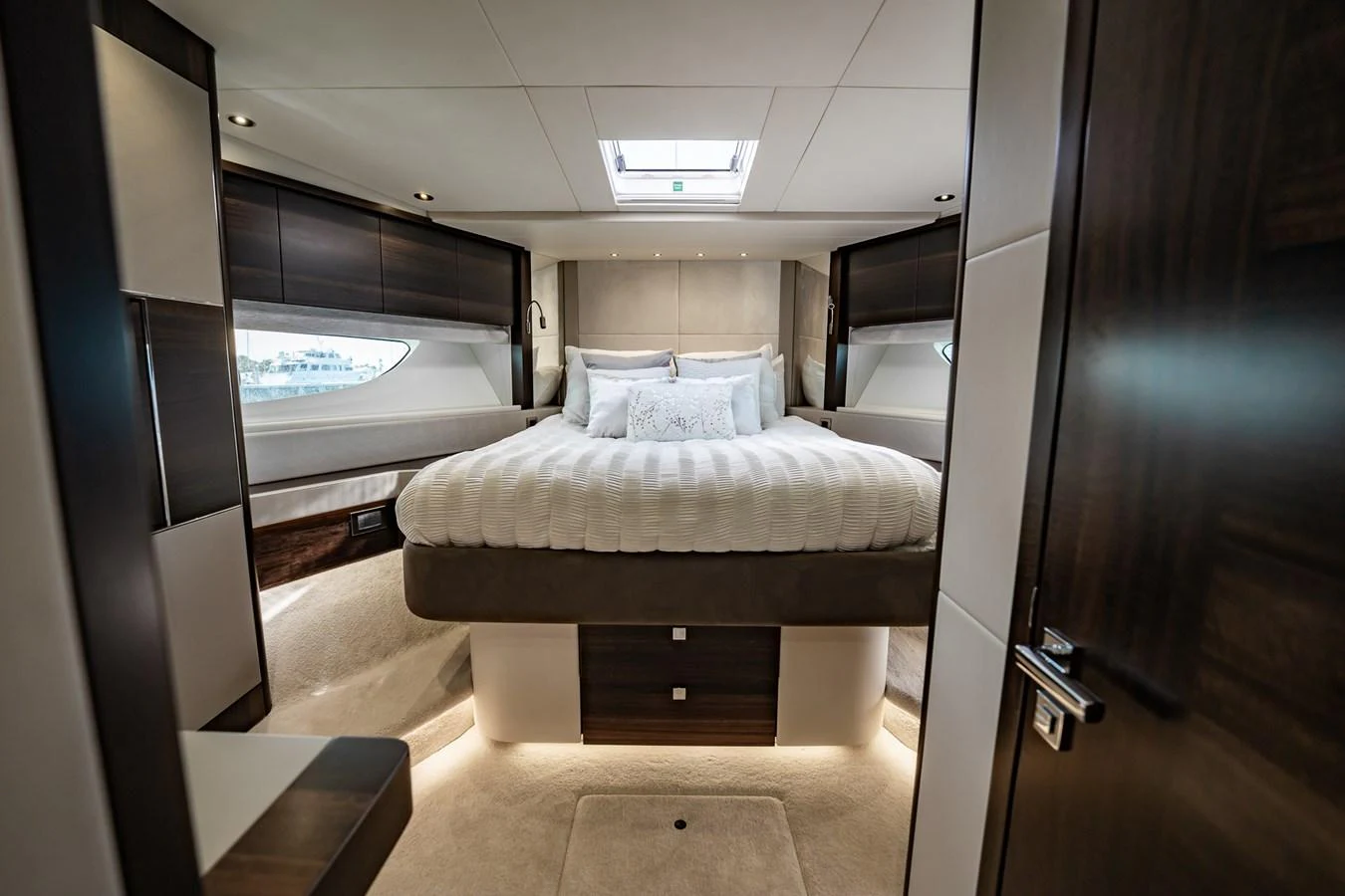 The master stateroom features a luxurious bed with elegant wood finishes and ample natural light. aboard BAZINGA Yacht for Sale