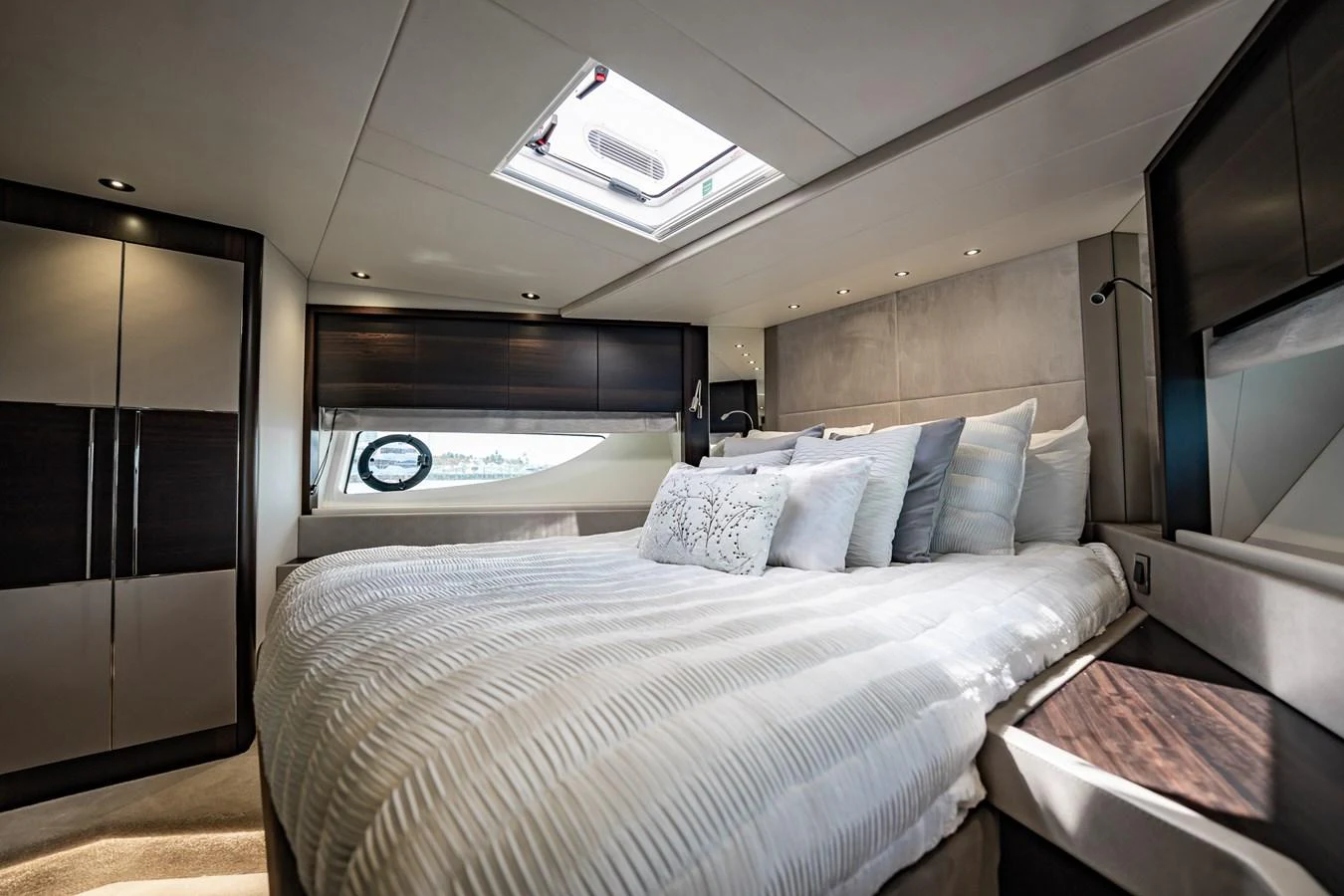 The stateroom features a luxurious bed with ample natural light from the skylight and side windows. aboard BAZINGA Yacht for Sale