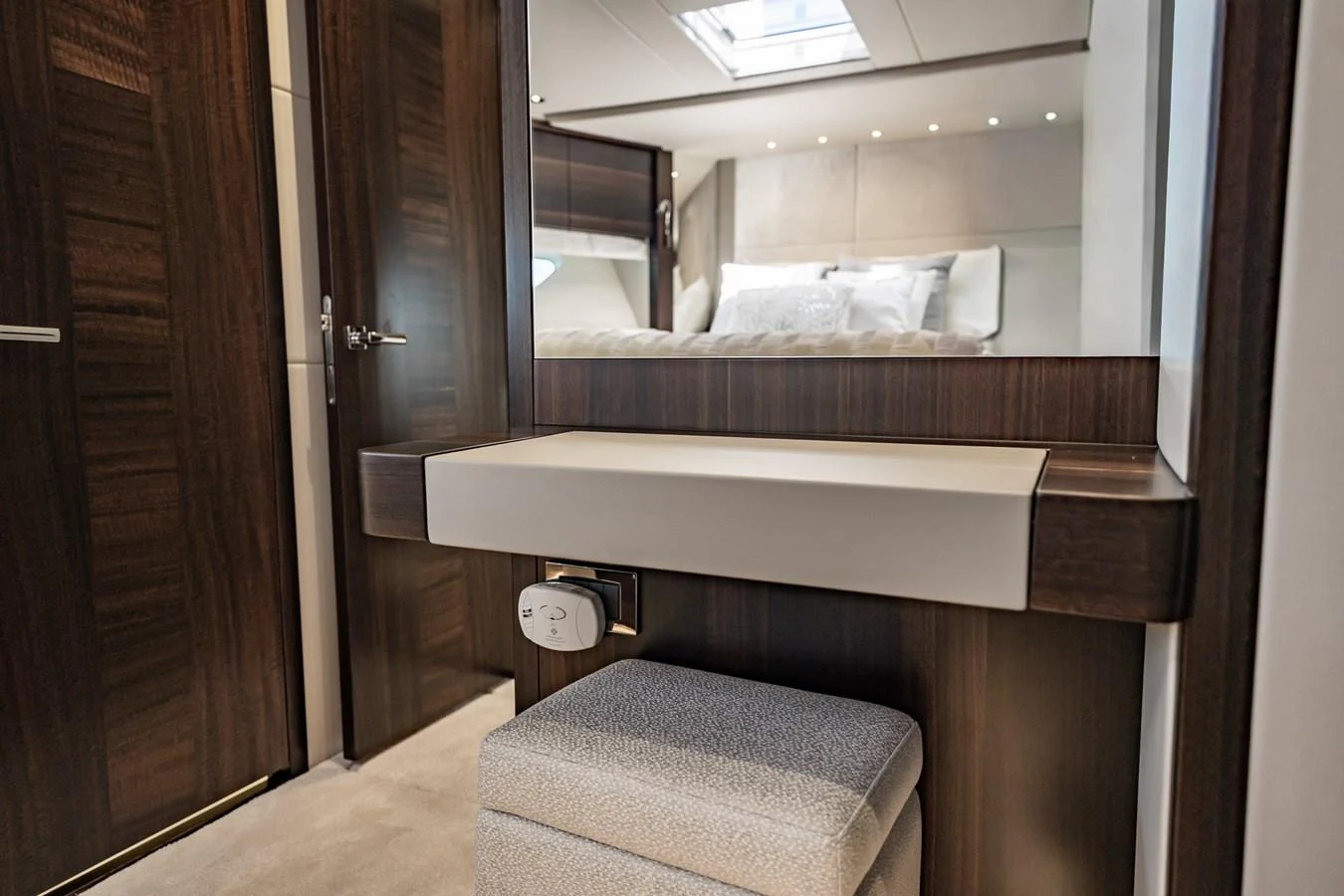 A luxurious stateroom featuring a vanity area with a plush stool and a glimpse of a cozy bed. aboard BAZINGA Yacht for Sale