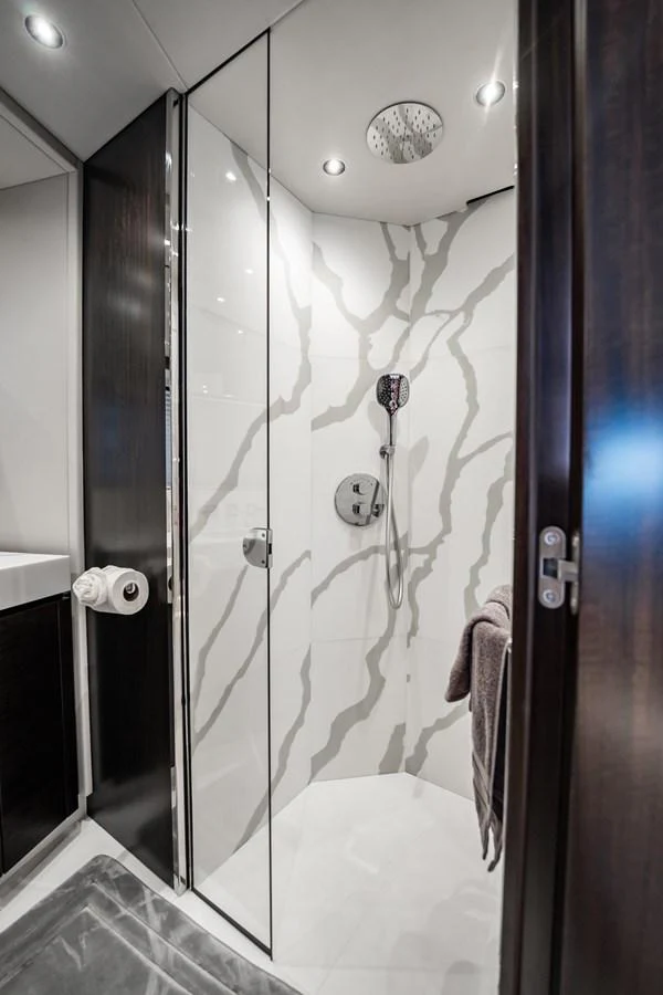 A modern yacht bathroom with a sleek glass shower enclosure and elegant fixtures. aboard BAZINGA Yacht for Sale