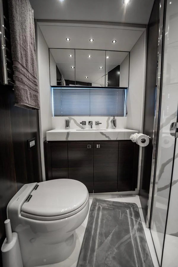 A sleek and modern yacht bathroom with dark wood accents and a large mirror. aboard BAZINGA Yacht for Sale