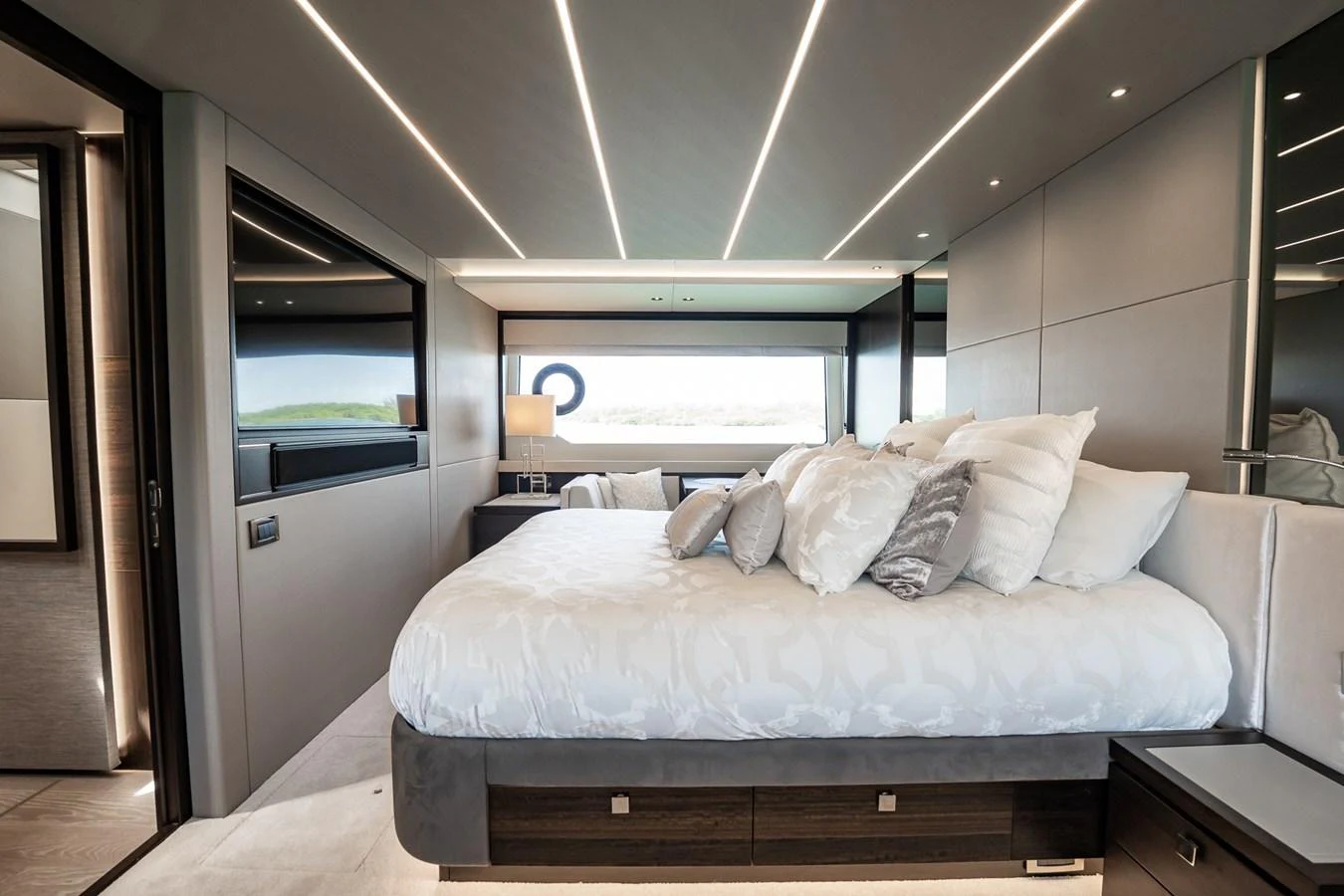 The stateroom features a luxurious bed with ample natural light from large windows. aboard BAZINGA Yacht for Sale