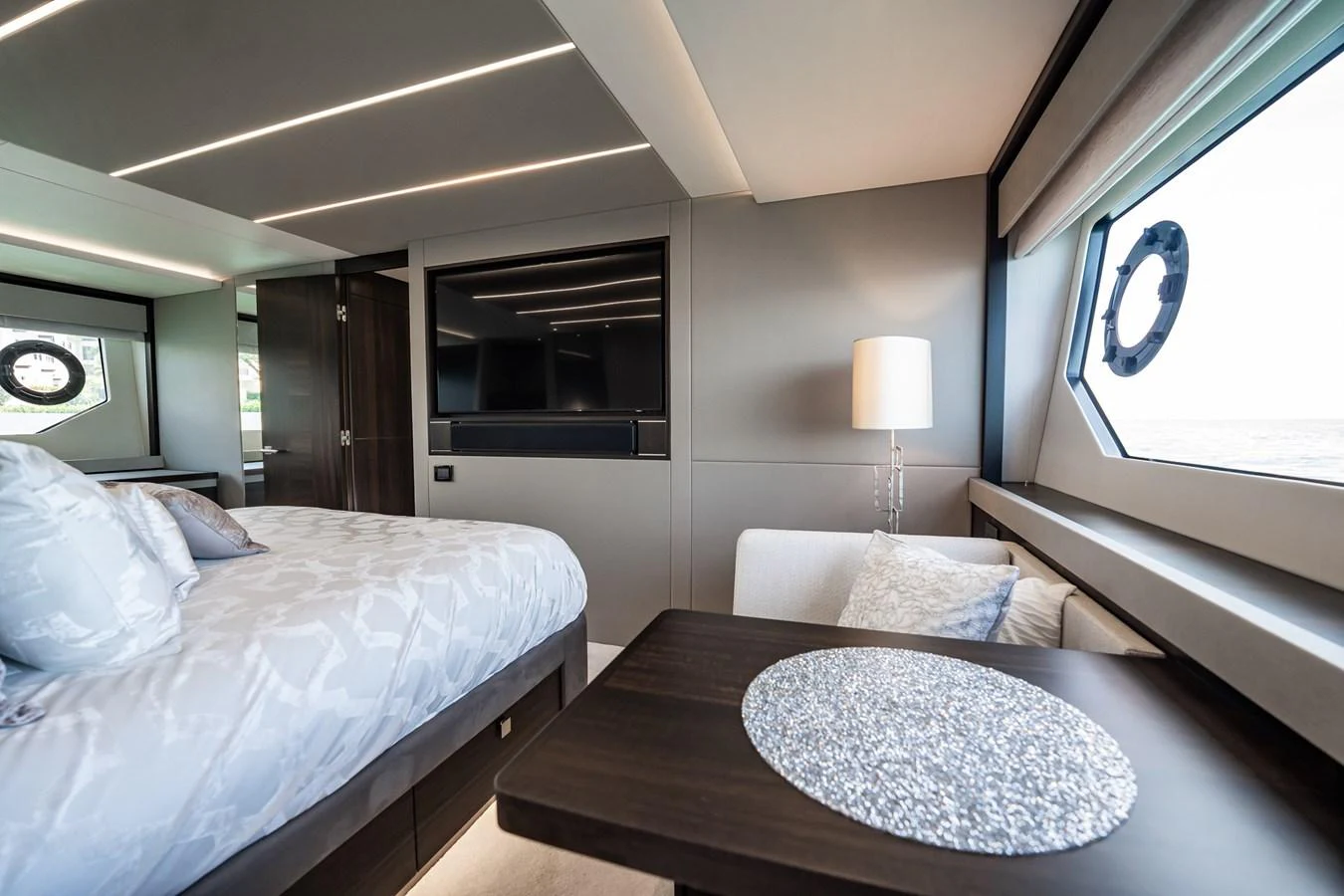 The stateroom features a luxurious bed, modern furnishings, and large windows for natural light. aboard BAZINGA Yacht for Sale