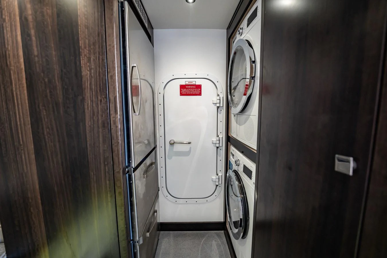 A compact laundry area with modern appliances and a sturdy door. aboard BAZINGA Yacht for Sale