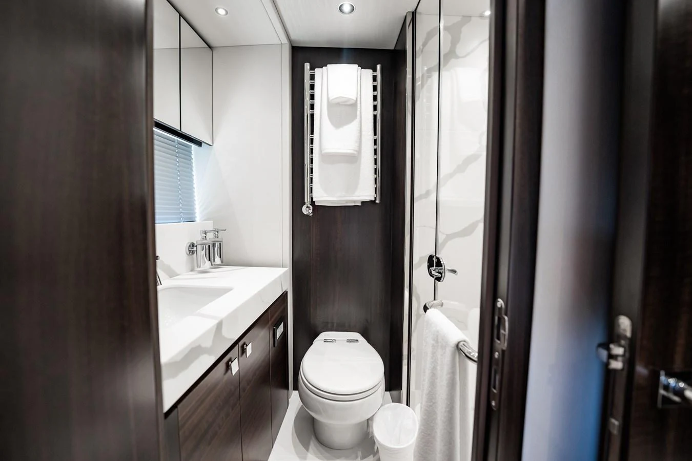 A sleek and modern yacht bathroom with dark wood accents and contemporary fixtures. aboard BAZINGA Yacht for Sale